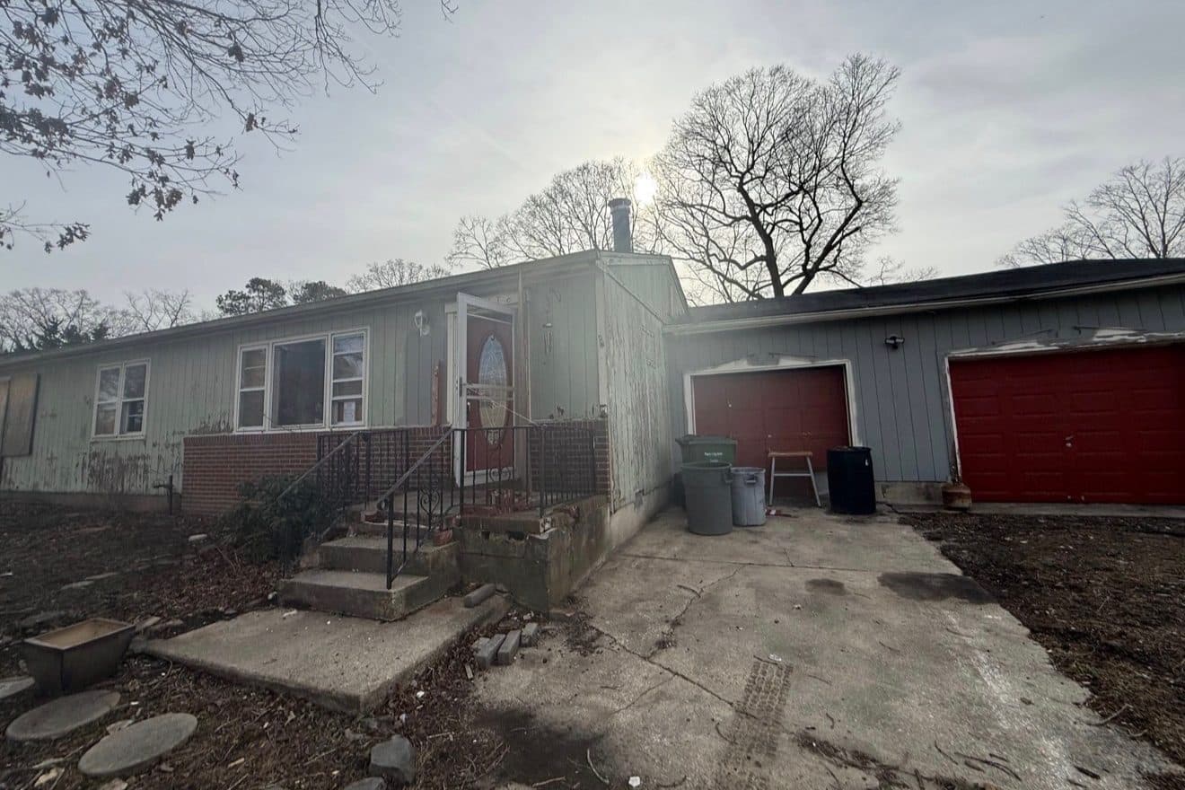 A weathered ranch house with peeling siding and a crumbling front step — the kind of house we buy as-is